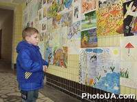 В помещении павильона птиц Киевского зоопарка проходит выставка детских работ, которые были присланы на международный конкурс "Сохраним деревья, сохраним птиц, сохраним Землю". Мальчик возле стенда с рисунками